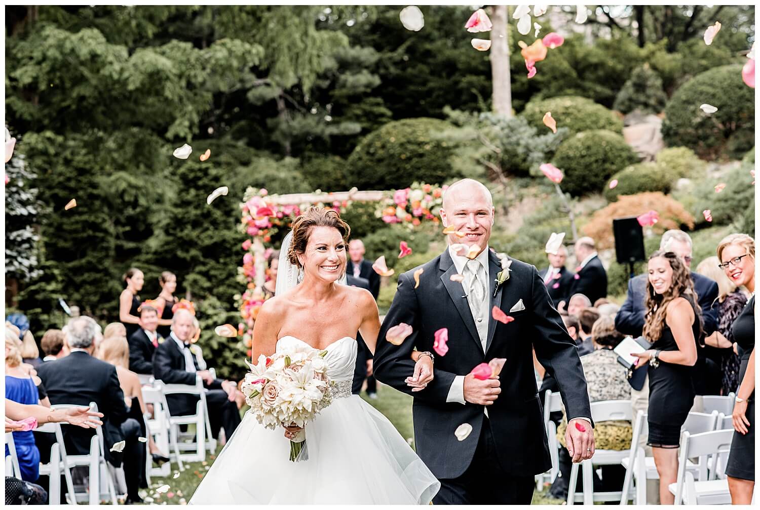 bride and groom walking down the aisle at their Cleveland Botanical Garden Wedding while guests throw flower petals at them