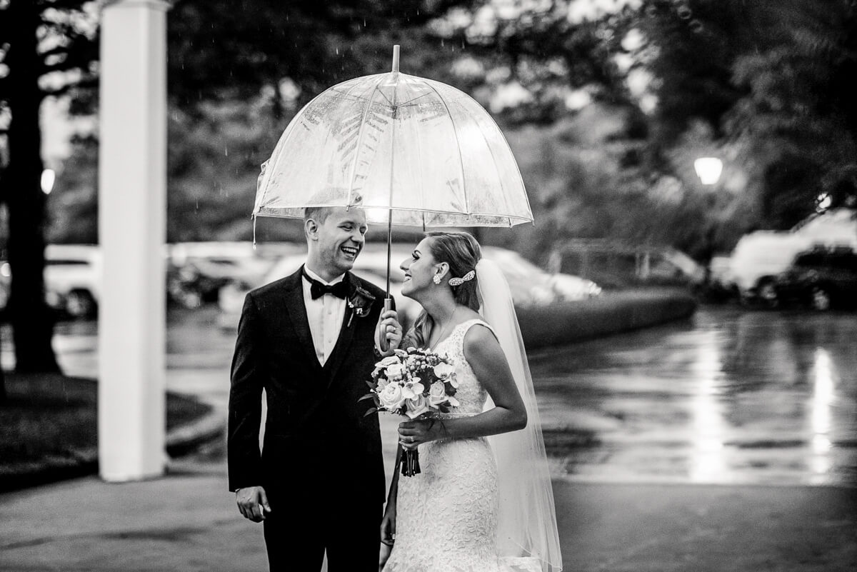 couple stands in rain under umbrella as part of their cleveland wedding planning