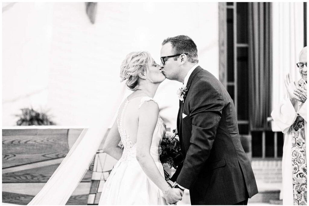 bride and groom first kiss in black and white at ariel pearl center wedding in cleveland