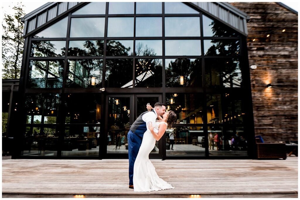 bride and groom kissing in front of sapphire creek winery on wedding day captured by three and eight photography
