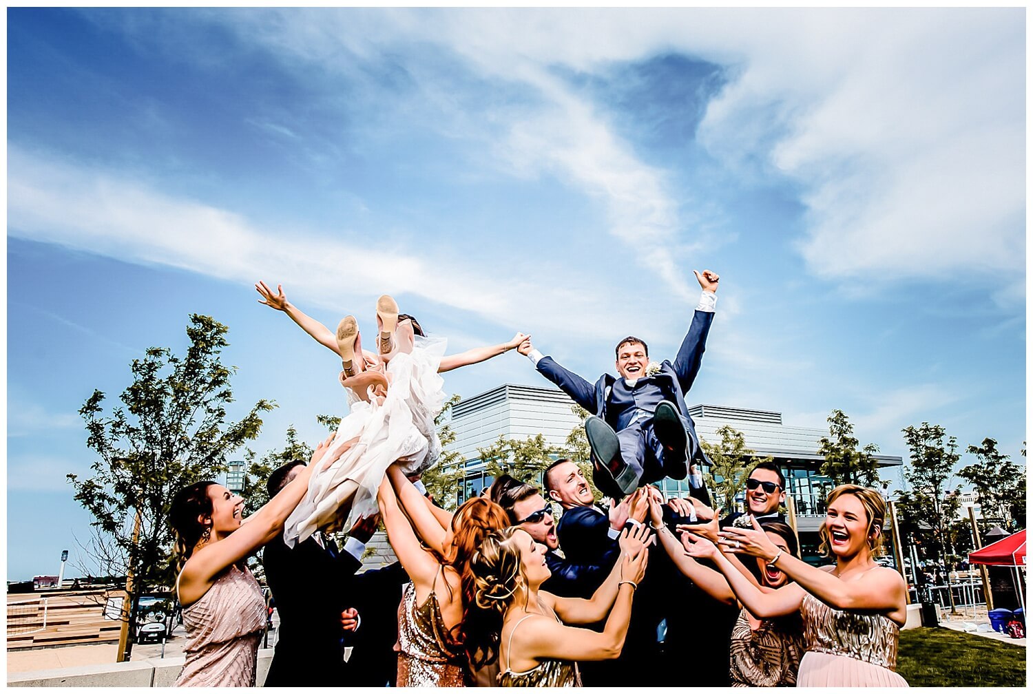 bridal party throwing bride and groom up in the air in ohio wedding photos in downtown cleveland captured by three and eight photography