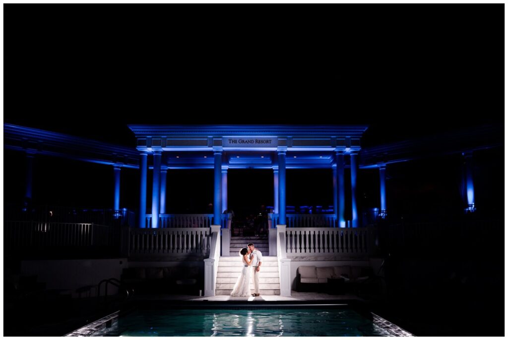 bride and groom standing in front of pool at the grand resort on avalon country club wedding
