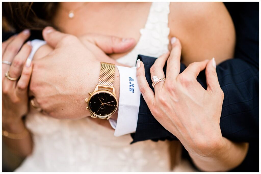 close up photo of bride and groom's arms while they are cuddled up showing of wedding jewelry