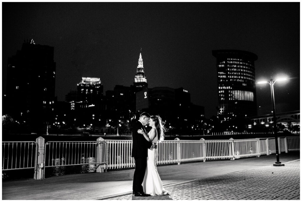 black and white photo of bride and groom in front of cleveland skyline at Windows on the River Wedding at night