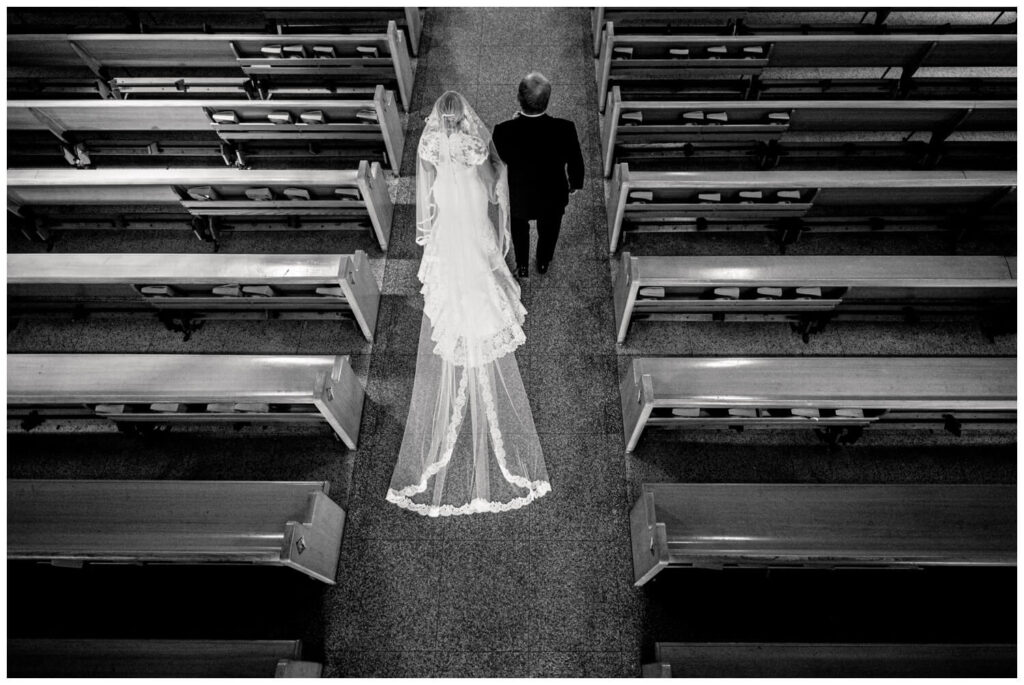 bride and father walking down aisle at church in black and white