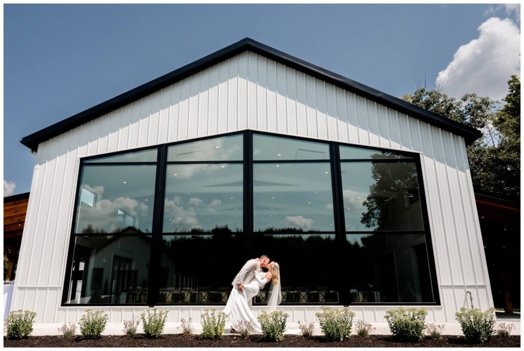 bride and groom kissing and dipping in front of large window at the wellspring