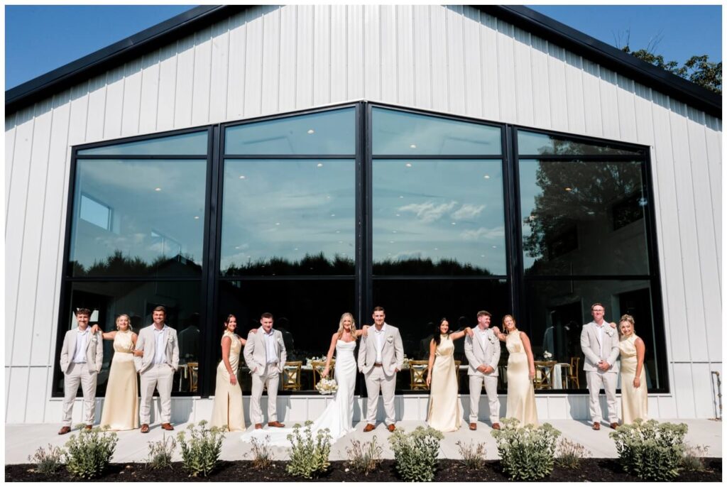 bridal party posing in front of large window at the wellspring in wooster