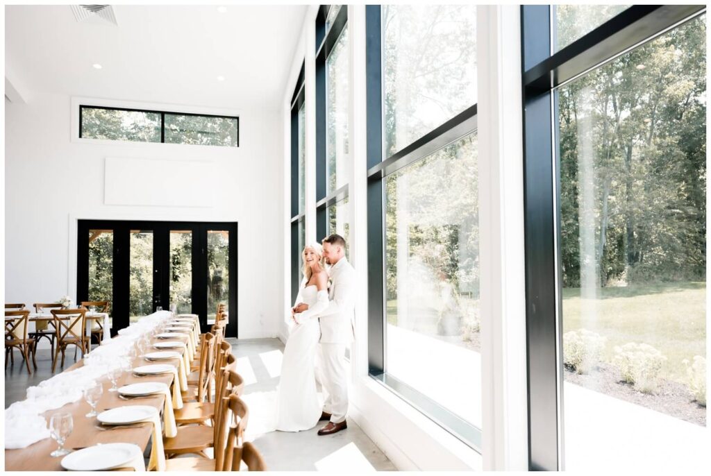 bride and groom leaning against window and laughing at the wellspring