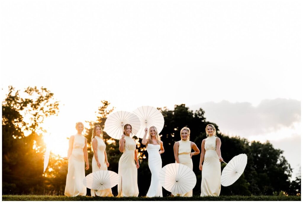 bride and bridesmaids holding parasols at sunset at the wellspring in wooster